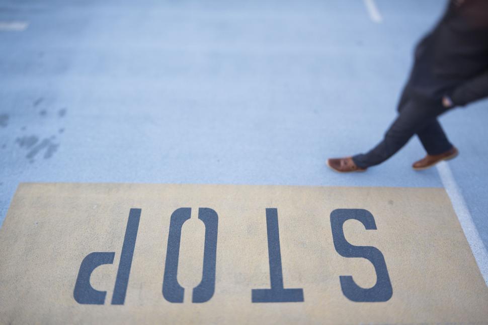 Free Image of Person Walking Across Parking Lot Next to Sign 