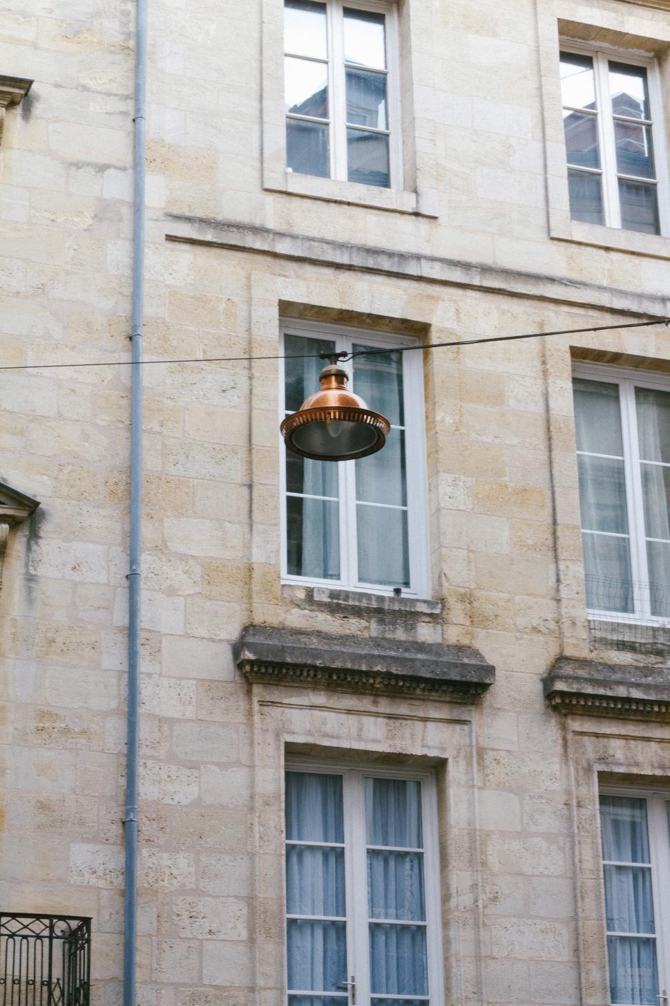 Free Image of Street Light Hanging From Wire in Front of Building 