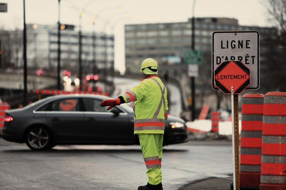Free Image of Construction Worker Directing Traffic on City Street 