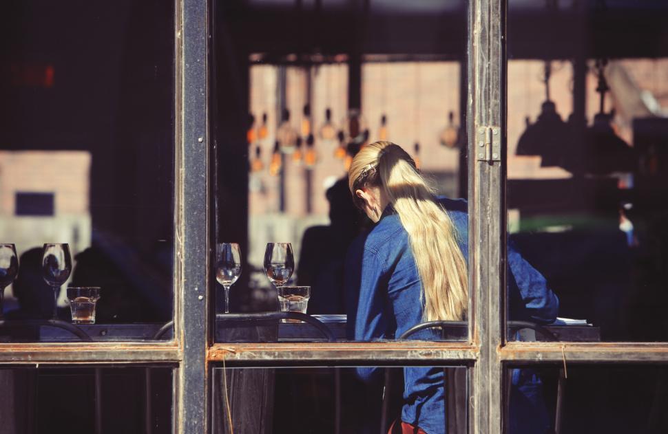Free Image of Woman With Long Blonde Hair Standing in Front of Window 
