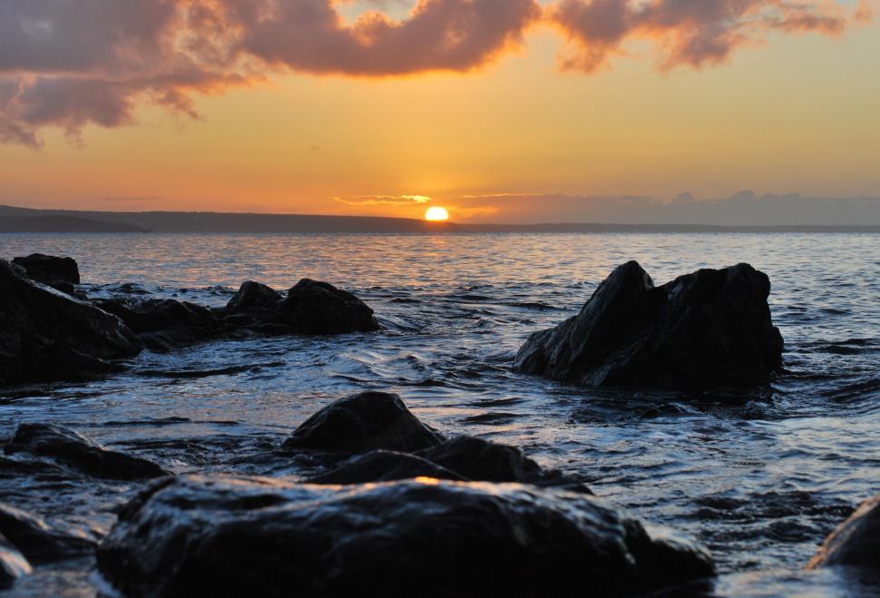 Free Image of Sunset Over Ocean With Rocks in Foreground 