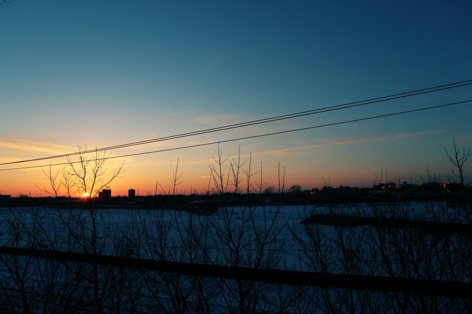 Free Image of The Sun Setting Over a Snowy Field 
