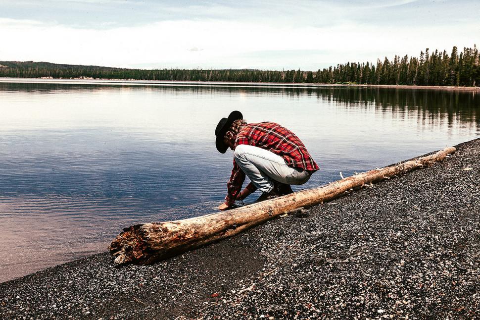 Free Image of Man Kneeling on Log by Lake 