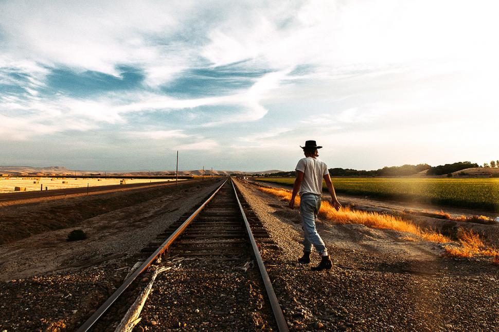 Free Image of Man in Hat Walking Down Train Track 