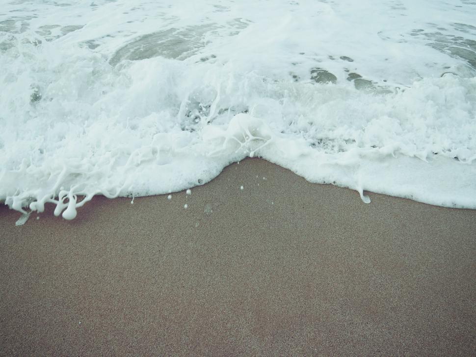 Free Image of A Wave Rolls in on a Sandy Beach 