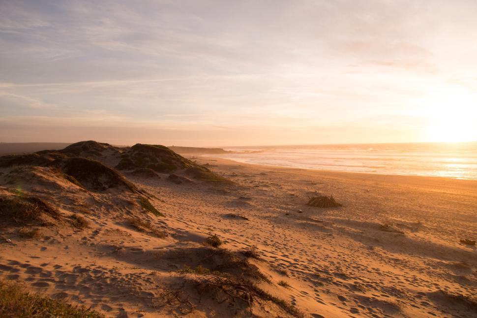 Free Image of The Sun Setting on a Sandy Beach 