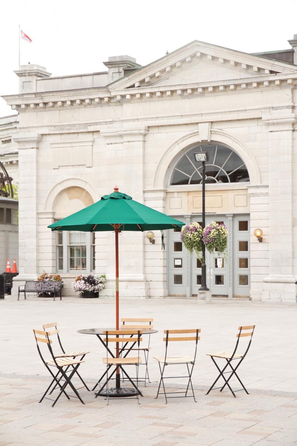 Free Image of Outdoor Dining Area With Umbrella in Front of Building 