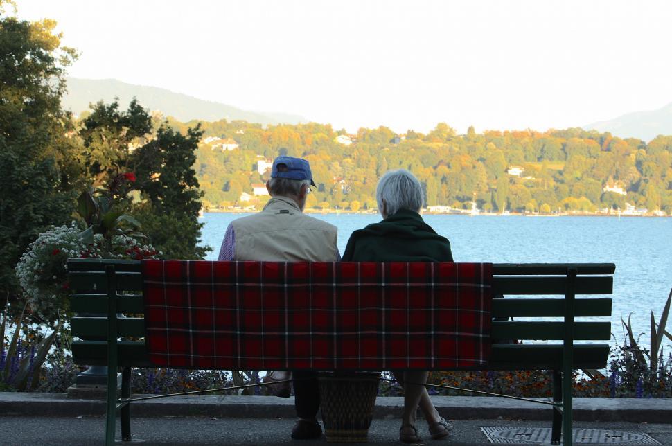 Free Image of Two People Sitting on a Bench by Lake 