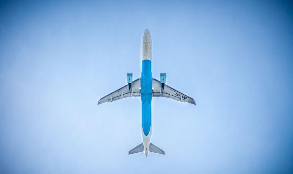 Free Image of Blue and White Jet Flying Through Blue Sky 