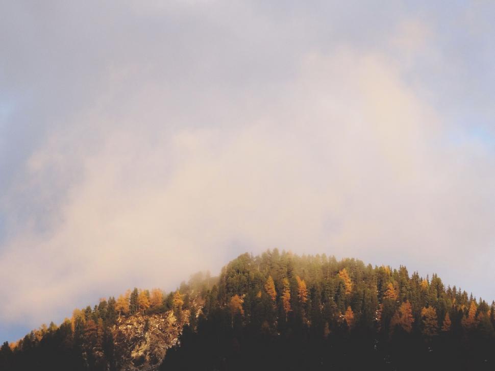 Free Image of Mountain Covered in Trees Under Cloudy Sky 