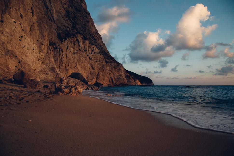Free Image of Sandy Beach Next to Rocky Cliff 