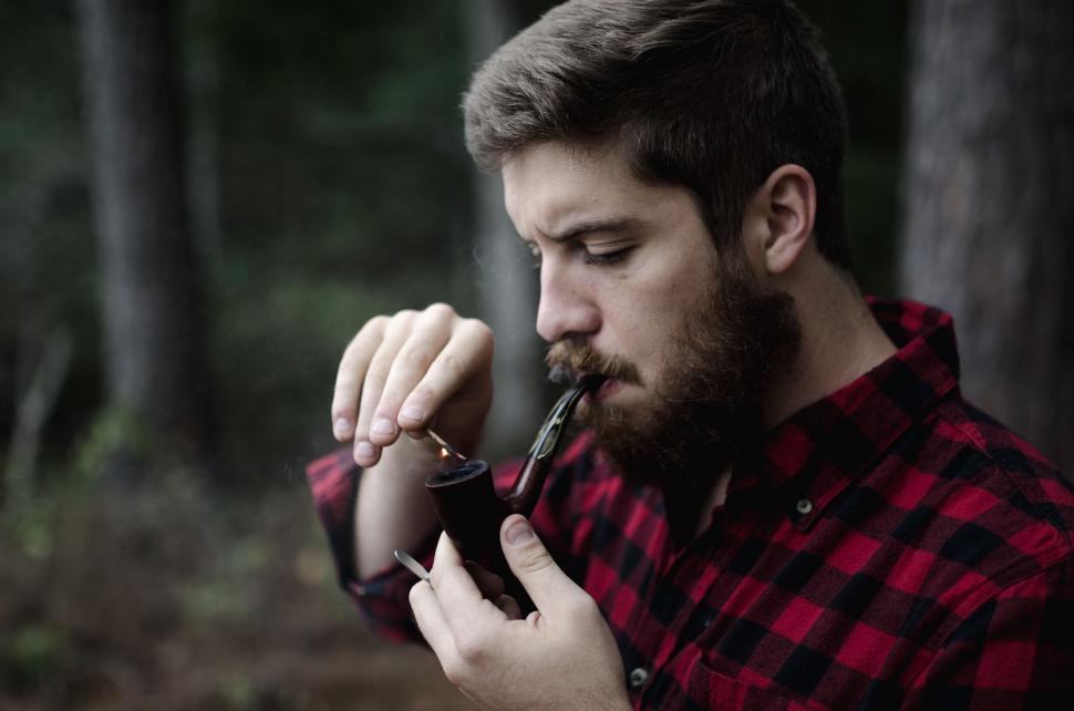 Free Image of Man in Red and Black Shirt Smoking a Pipe 