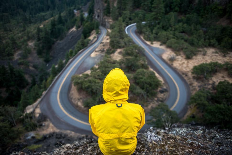 Free Image of Person in Yellow Raincoat Looking at Winding Road 