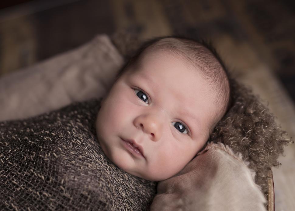 Free Image of Baby Wrapped in Blanket Looking at Camera 