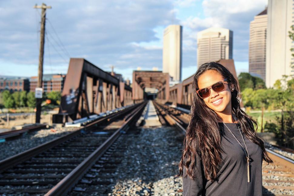 Free Image of Woman Standing on Train Tracks in Front of City 