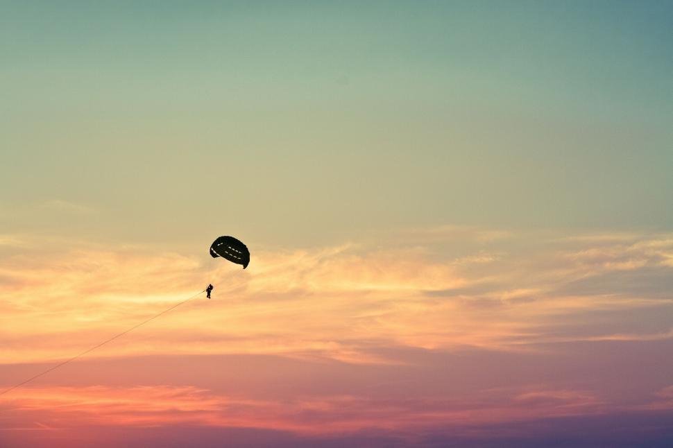 Free Image of Person Parasailing in Sky at Sunset 