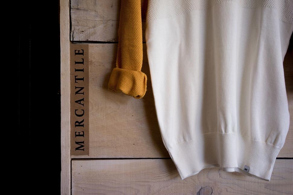 Free Image of White Sweater Hanging on Wooden Wall 
