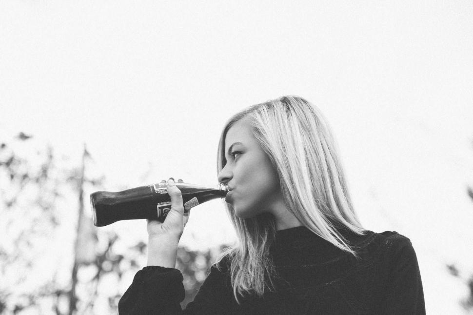 Free Image of Woman With Long Blonde Hair Drinking From a Bottle 