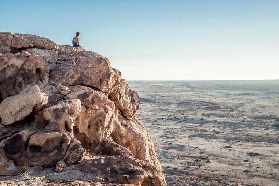 Free Image of Man Sitting on Top of a Large Rock 