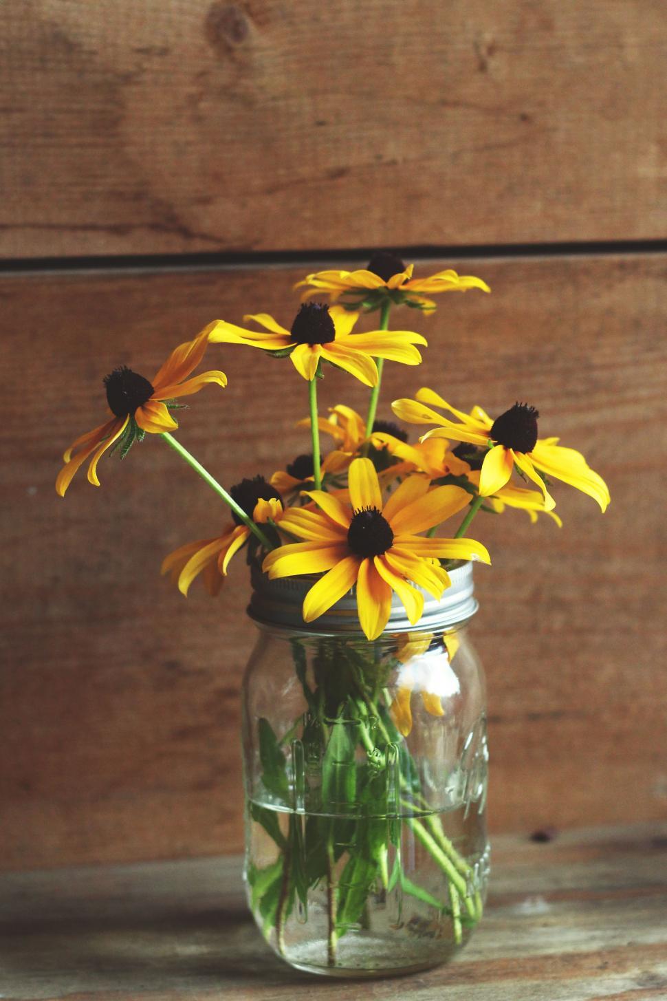 Free Image of Mason Jar Filled With Yellow Flowers on Wooden Table 