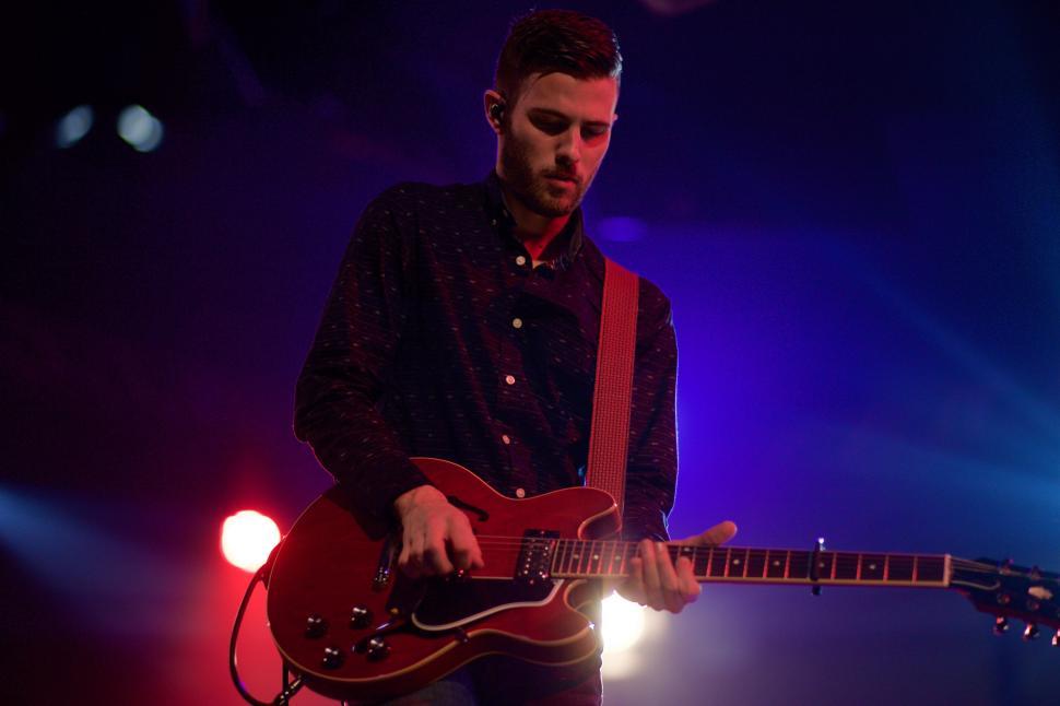 Free Image of Man Playing a Red Guitar on Stage 