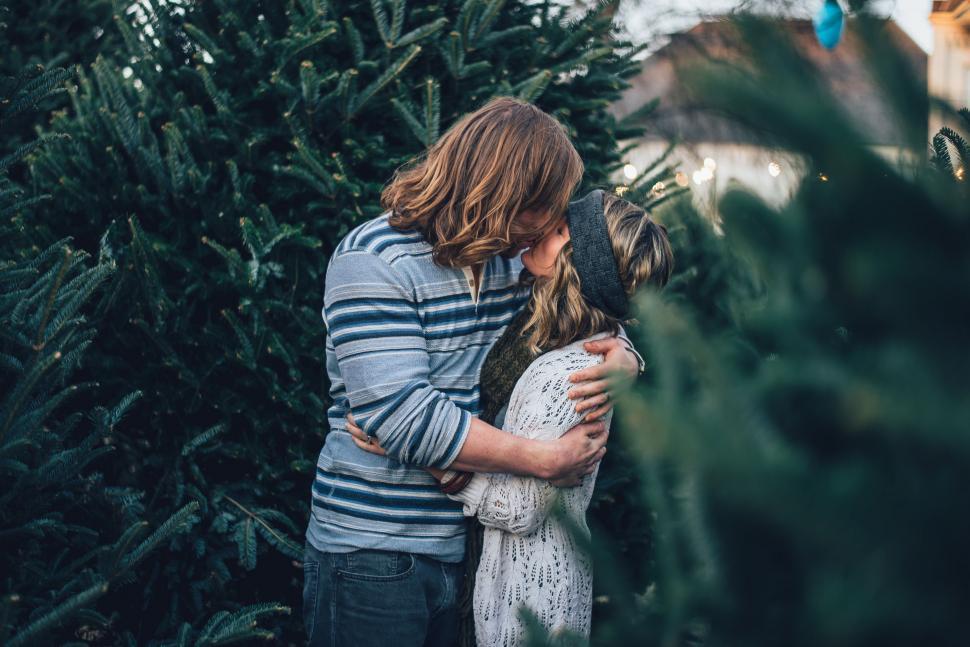 Free Image of Couple Kissing in Front of a Christmas Tree 