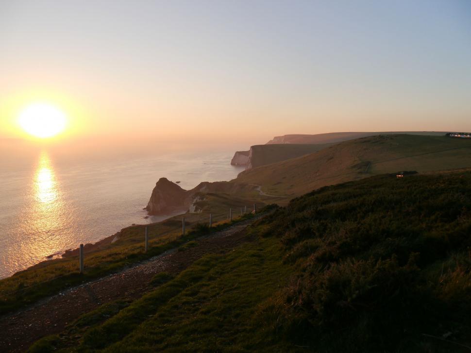 Free Image of Sun Setting Over Ocean on Hill 