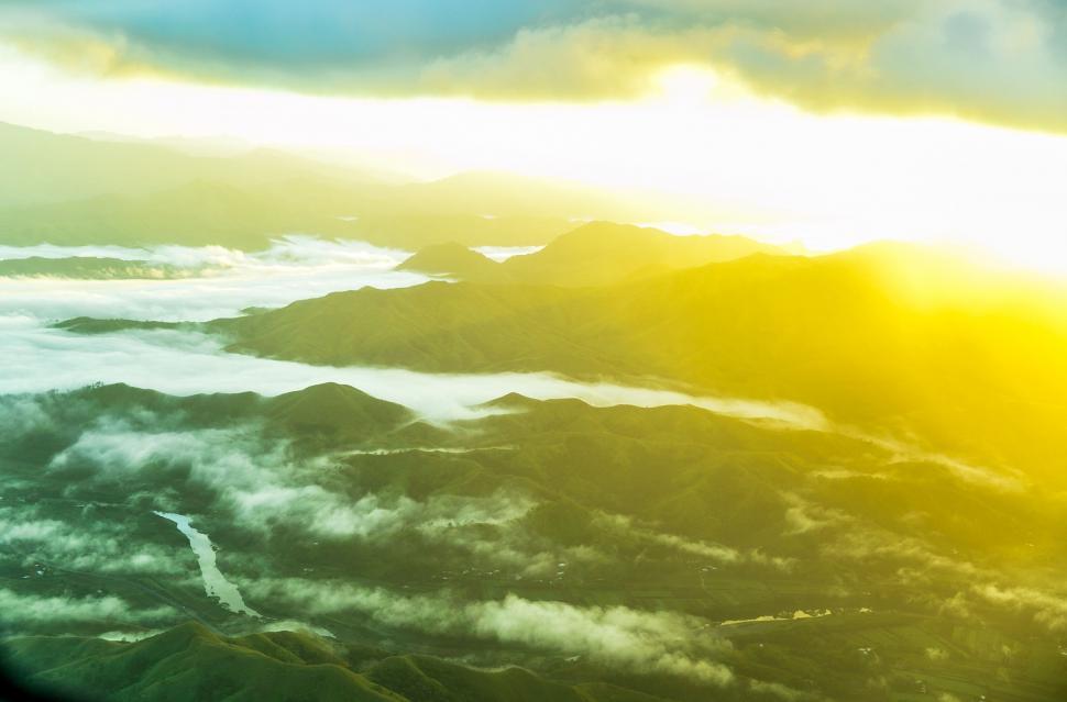 Free Image of Sun Shining Through Clouds Over Mountains 