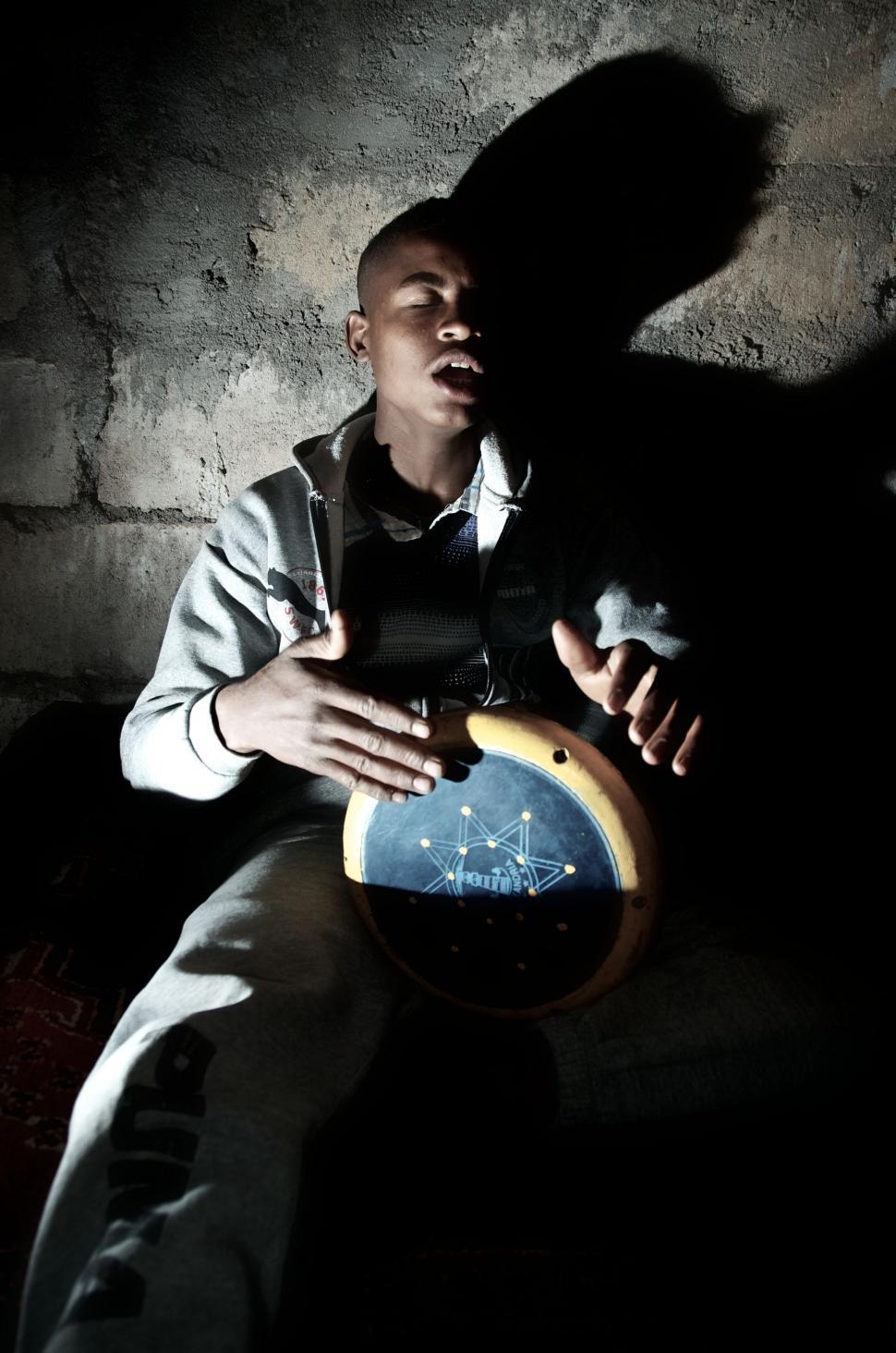 Free Image of Man Sitting in the Dark Holding a Clock 