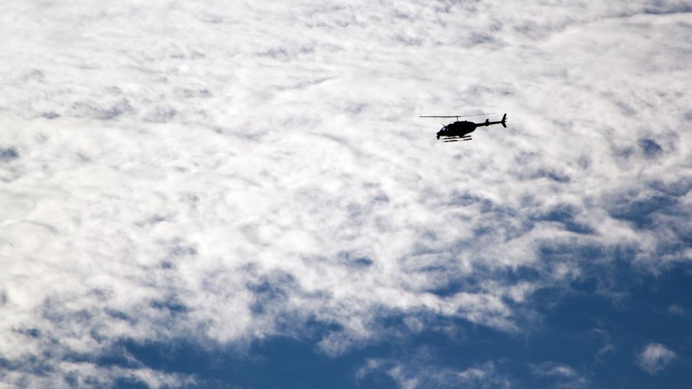 Free Image of Helicopter Flying Through Cloudy Blue Sky 