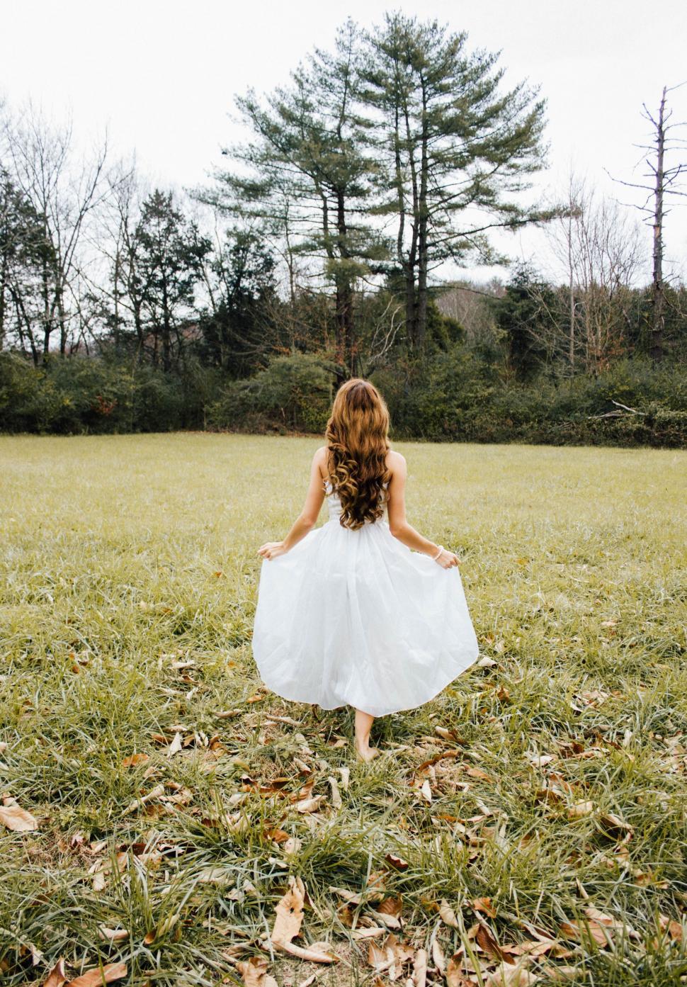 Free Image of Young Girl in White Dress Walking Through Field 