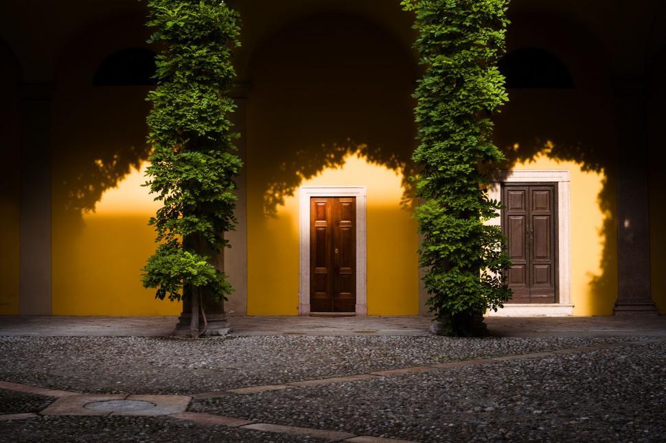 Free Image of Yellow Building With Brown Door and Trees 