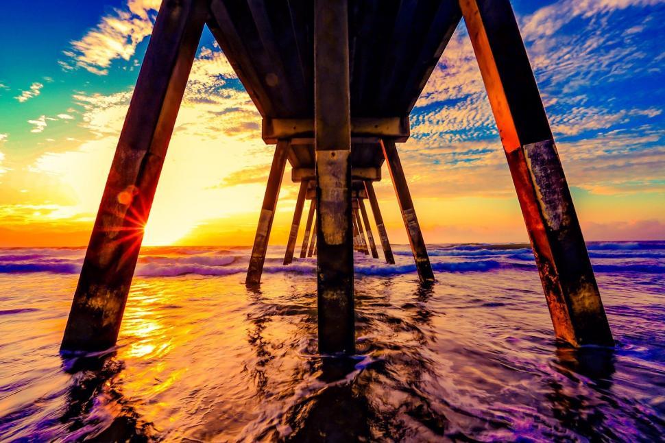 Free Image of Sun Setting Over Ocean Under Pier 