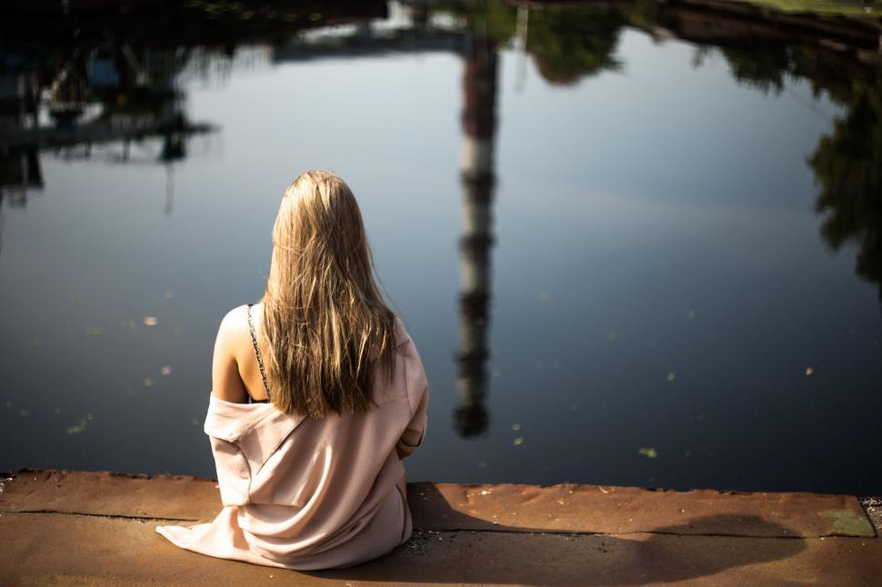 Free Image of Woman Sitting on Edge of Body of Water 