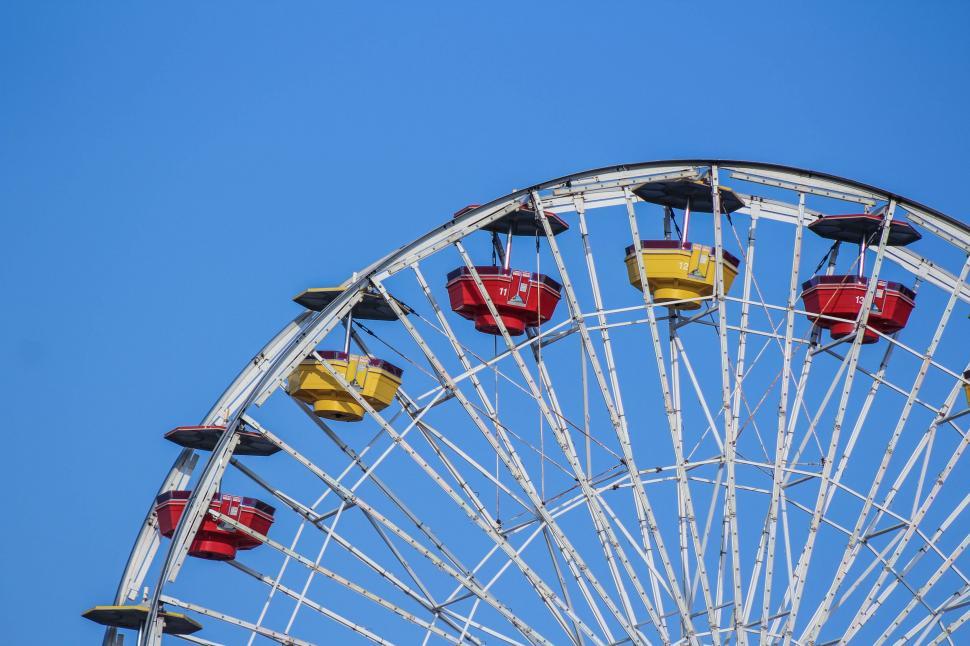Free Image of Ferris Wheel With Red and Yellow Seats Against a Blue Sky 