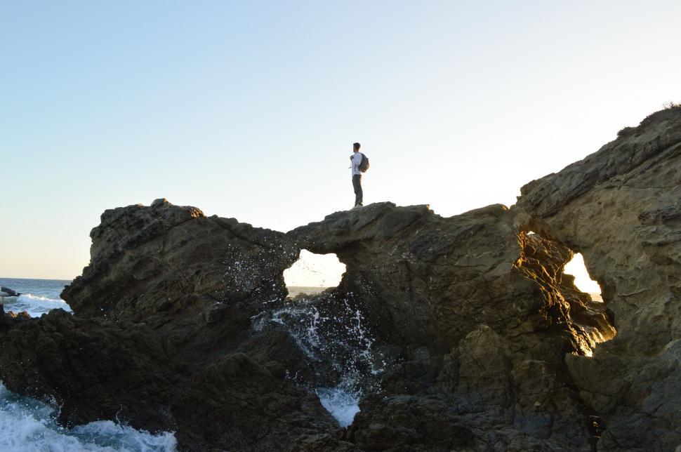 Free Image of Man Standing on Rocky Cliff by Ocean 