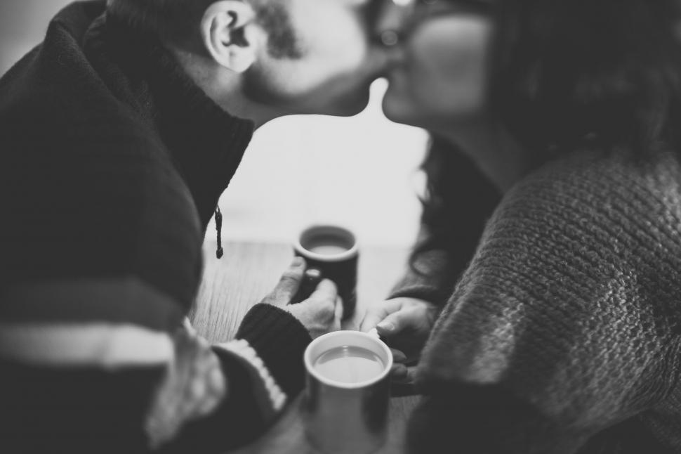 Free Image of Man and Woman Kissing While Holding Coffee Cups 