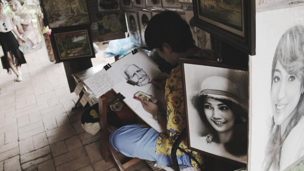 Free Image of Woman Sitting in Chair Next to Drawing of a Woman 
