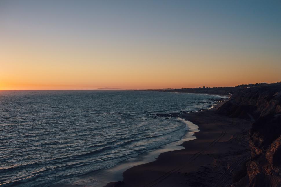 Free Image of Sun Setting Over Ocean on Beach 