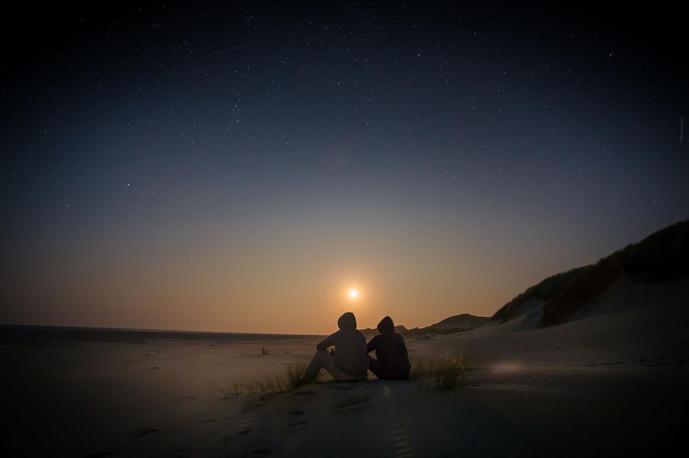 Free Image of Couple Sitting on Sandy Beach 
