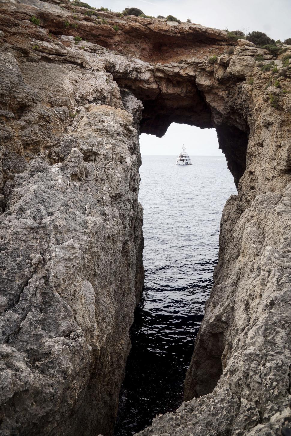 Free Image of Boat Sailing Through Hole in Rocks 