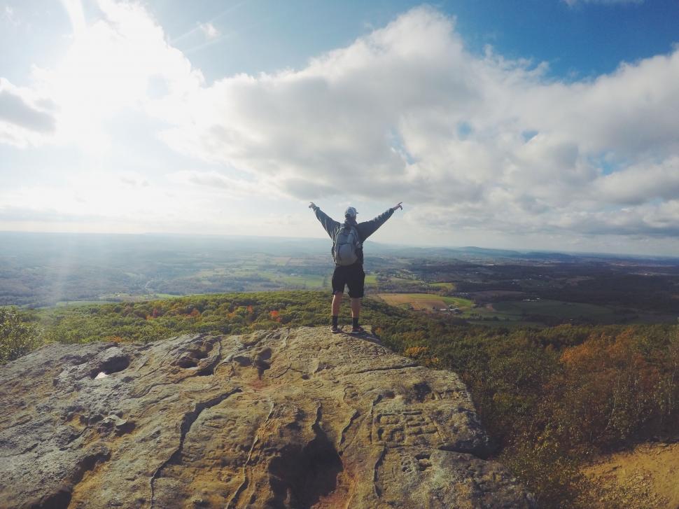 Free Image of Man Standing on Top of Mountain With Arms Wide Open 