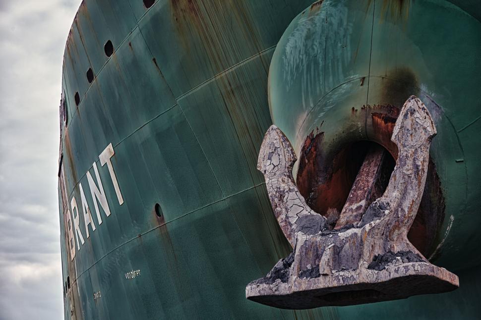 Free Image of Large Green Ship With Rust on Its Side 