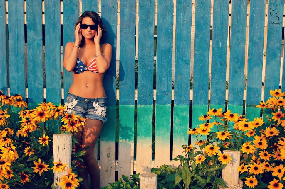 Free Image of Woman Standing in Front of Fence With Sunflowers 