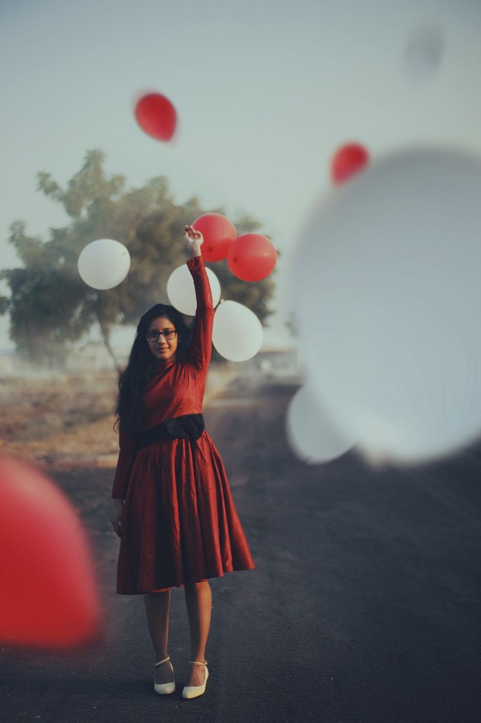 Free Image of Woman in Red Dress Holding Bunch of Balloons 