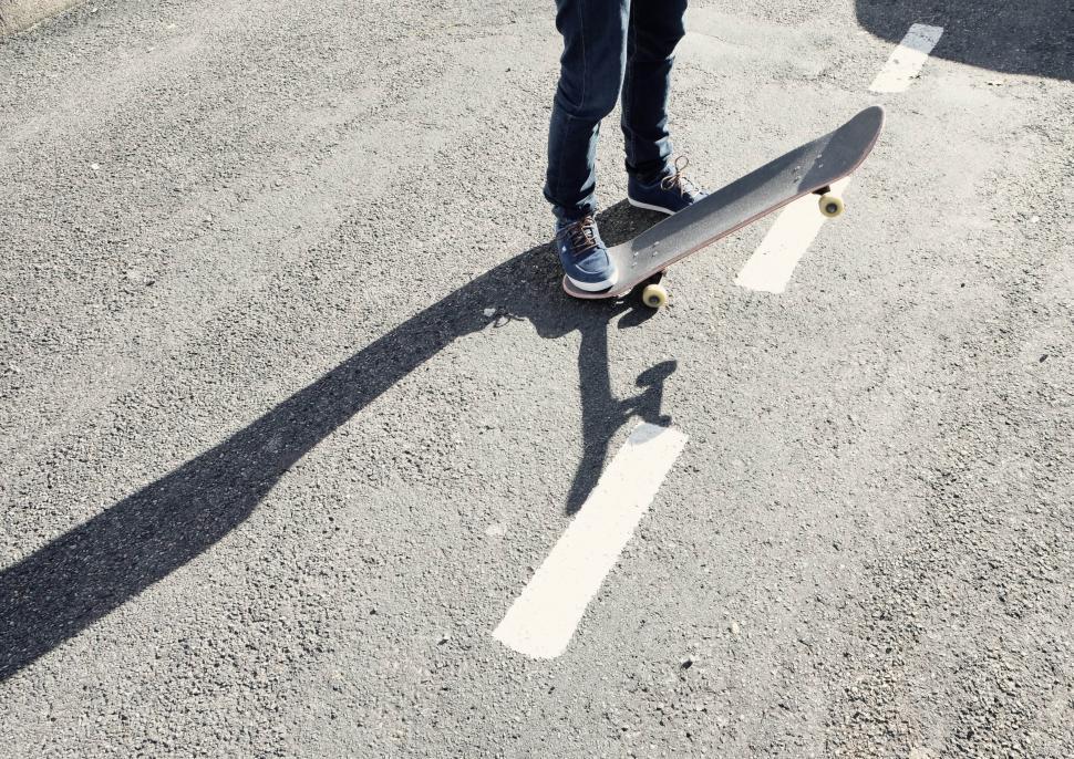 Free Image of Person Standing on Skateboard in Parking Lot 