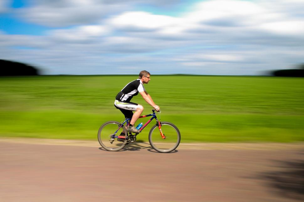 Free Image of Man Riding Bike Down Dirt Road 