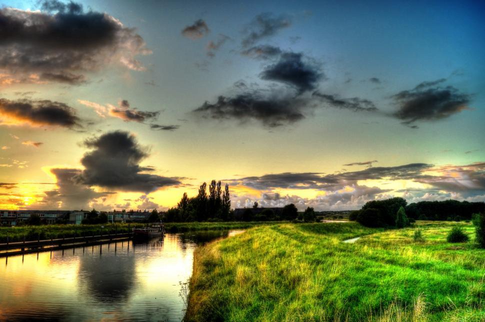Free Image of River Flowing Through Lush Green Field Under Cloudy Sky 
