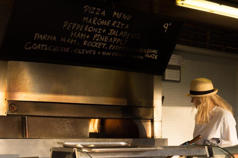Free Image of Woman Standing in Front of a Pizza Oven 