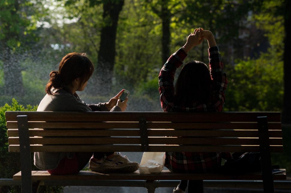 Free Image of Two People Sitting on a Bench in a Park 